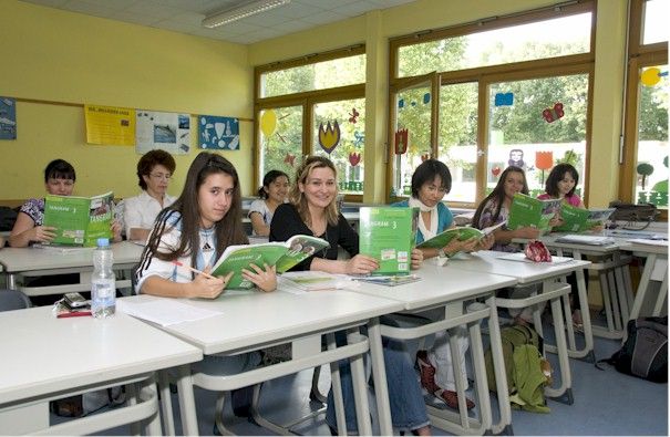 Schuelerinnen in einem Klassenzimmer, die im Buch lesen.