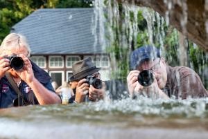 Drei engagierte Herren mit Fotoapparaten beugen sich zum Bilder machen über einen Brunnen